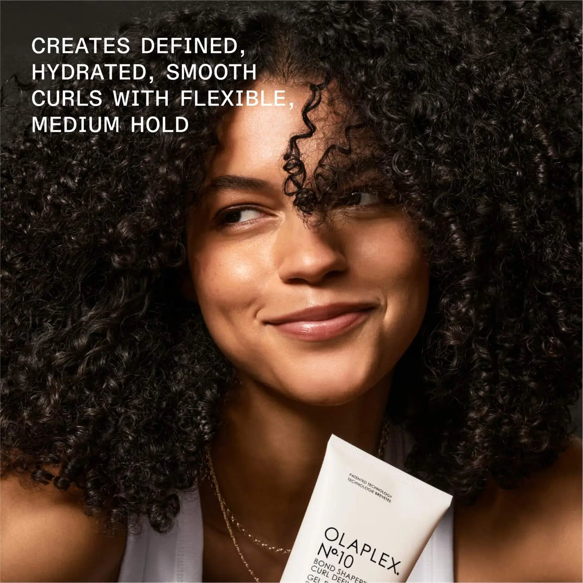 Olaplex No.10 Bond Shaper Curl Defining Gel 200 ml — model with defined curls holding the tube