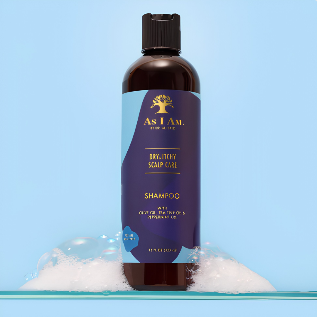A 12 fl oz bottle of As I Am By Dr. Judd Dry/Litchy Scalp Care Shampoo, standing upright on a bed of white foam against a light blue background.