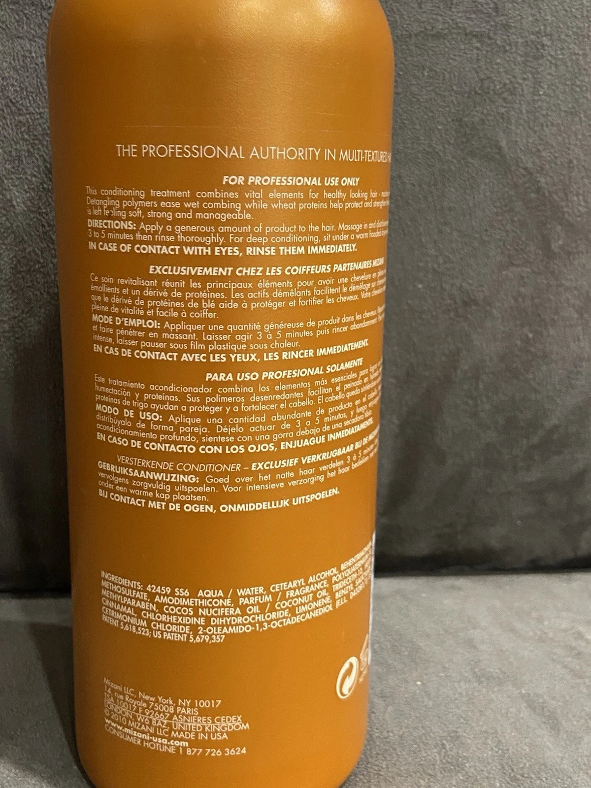 Orange MIZANI Thermasmooth conditioner bottle with white text, product image, and brand logo on a plain gray background.