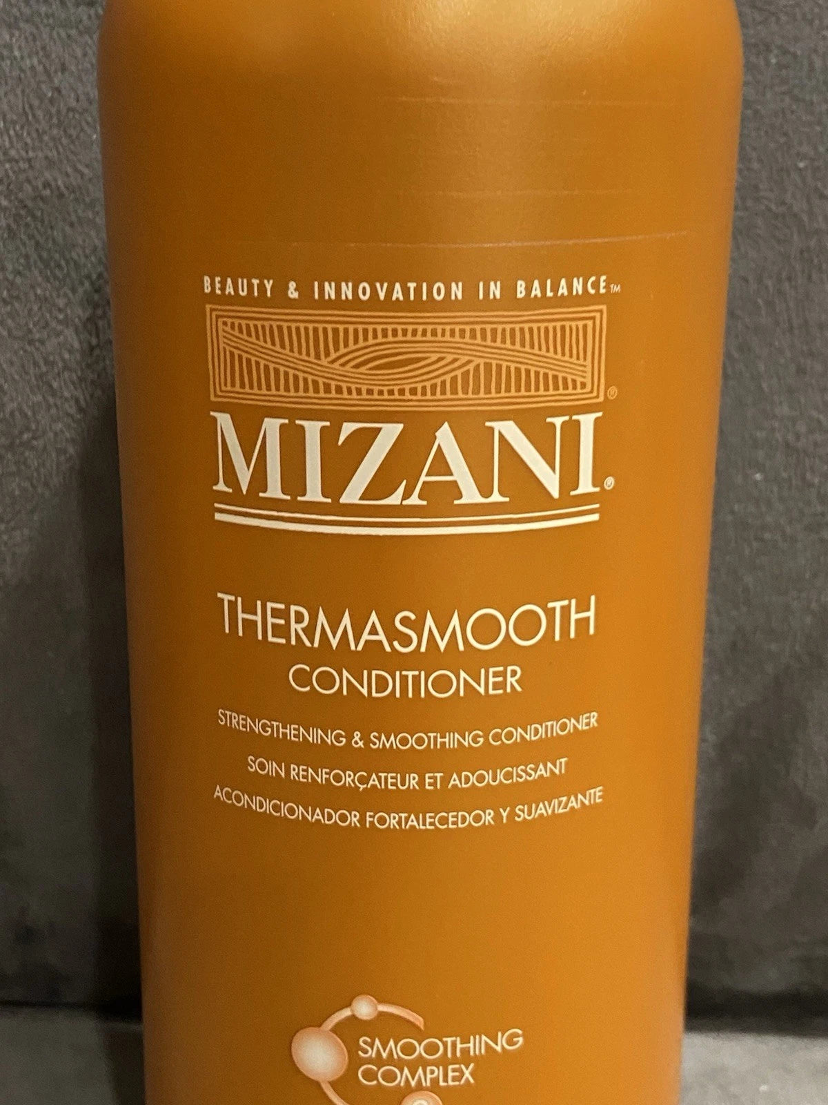 Orange MIZANI Thermosmooth Conditioner bottle with black text, product image, and “Strengthening Smoothing Hair Conditioner” label.
